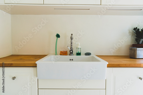 Kitchen sink with utensils: sponge, soap and brush.