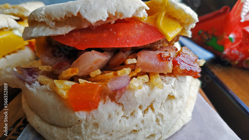 Delicioso sandwich con queso, tomate, panceta, papas y cebolla