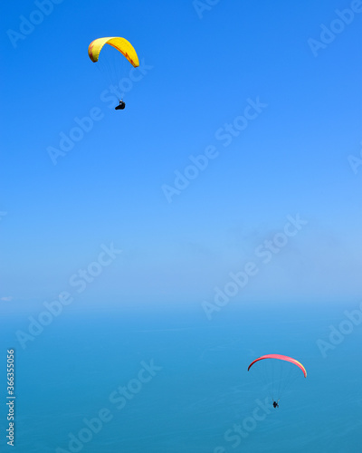 Two people glide through the sky with paragliding.