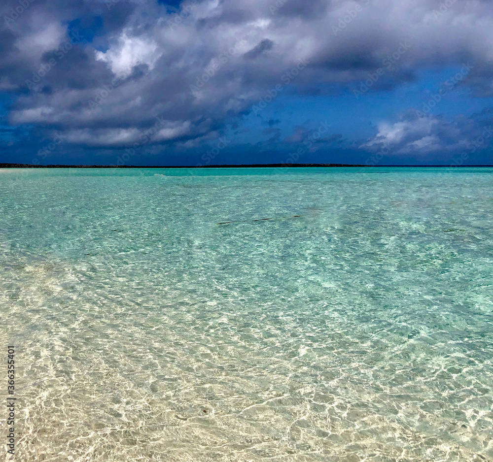 Ocean shoreline with yellow sand and turquoise water and storm clouds