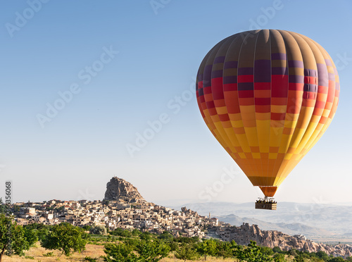 Big colorful hot air balloon flying against Nevsehir town in Cappadocia, Turkey