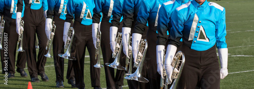 Marching band on a field. Marching in a line with trumpets and other instruments playing music.