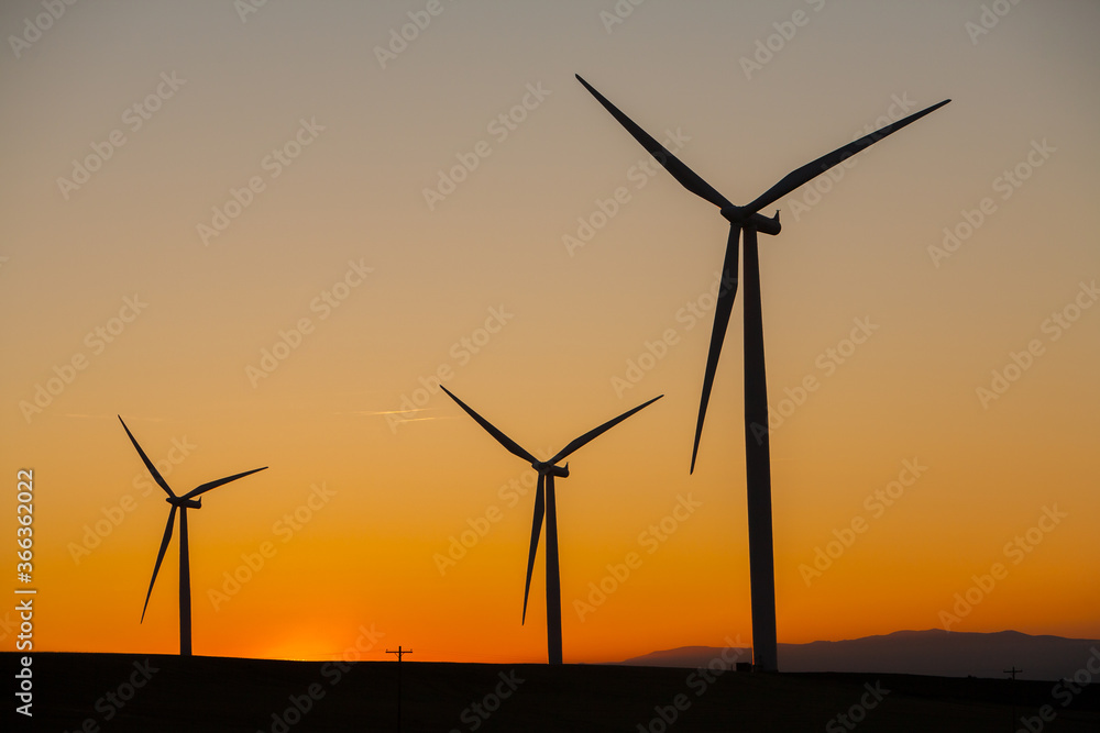 Wind generators in Sherman County Oregon are shown against an orange sunset sky. Located a few miles south of the Columbia River Gorge. Wind generators in Sherman County Oregon are shown against an orange sunset sky. Located a few miles south of the Columbia River Gorge.