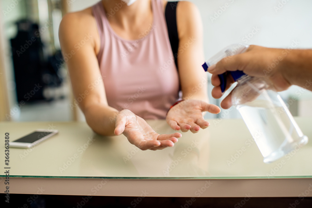 Close-up of woman getting her hands disinfected at reception desk.