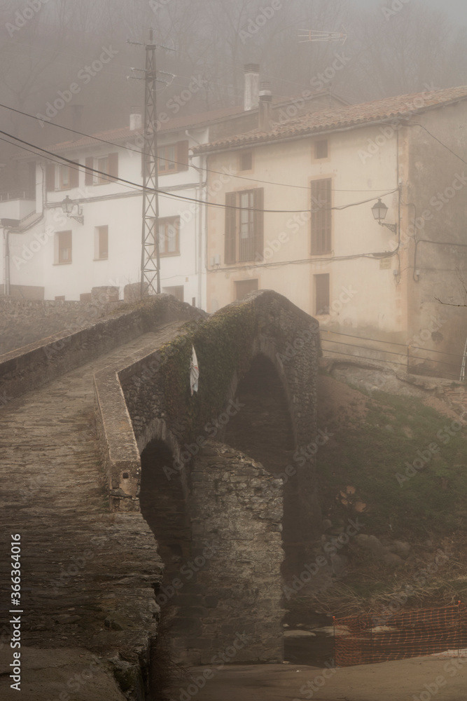 Foggy town and medieval bridge