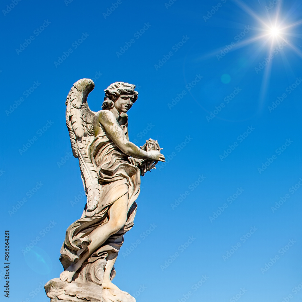 Obraz premium Pomnik pomnika anioła na tle błękitnego nieba i słońca