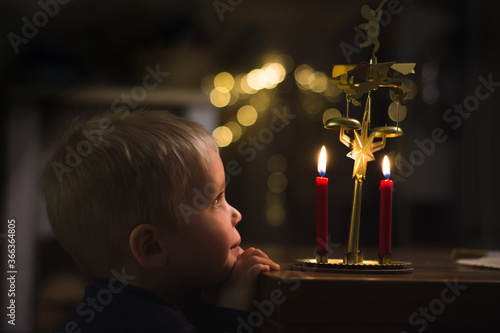 Little boy is looking at candels and angel chimes, christmas decoration angel chimes photo