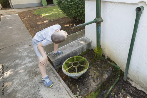 Ein Junge trinkt Wasser aus einem Brunnen  photo