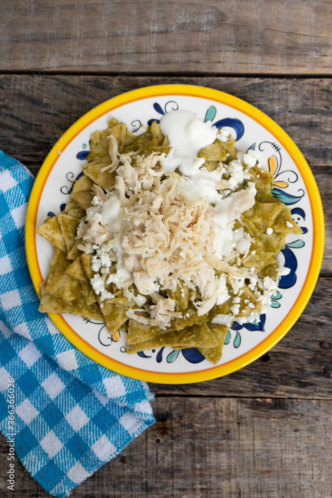 Mexican green chilaquiles with chicken and cheese on wooden background Mexican green chilaquiles with chicken and cheese on wooden background