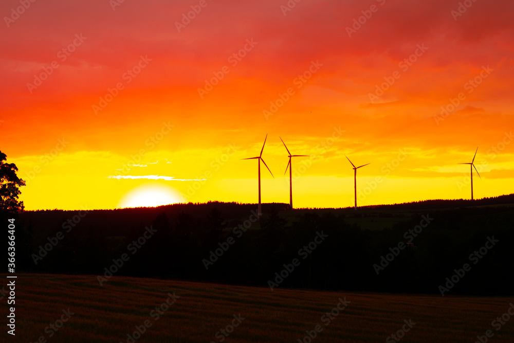 Obraz premium Orange Sky Sunset with wind turbines in the background
