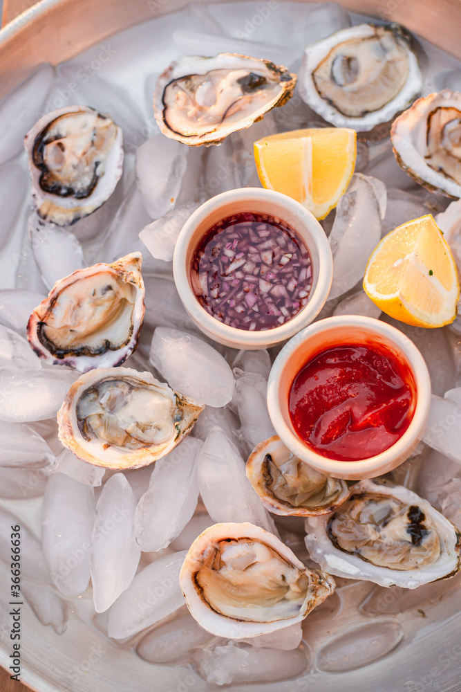 Oyster platter with minced shallot in red vinegar and horseradish tomato sauce. Seafood plate. Ocean meal. Raw seafood. Lemon slices. Fresh and nutritional dinner. Luxury meal. Fancy dinner. Oyster platter with minced shallot in red vinegar and horseradish tomato sauce. Seafood plate. Ocean meal. Raw seafood. Lemon slices. Fresh and nutritional dinner. Luxury meal. Fancy dinner.