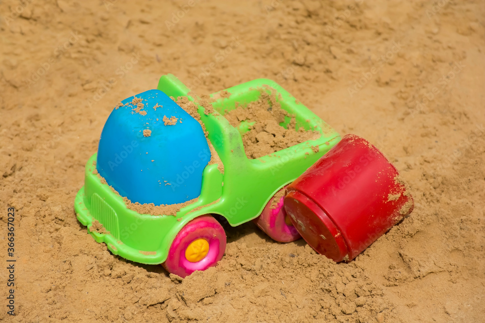 many different colorful toys in the sand on the playground many different colorful toys in the sand on the playground