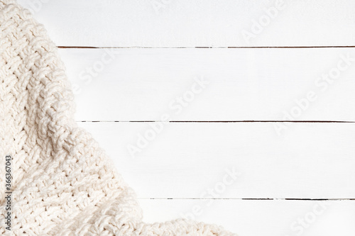 Warm light beige wool fabric on a white wooden background with copy space