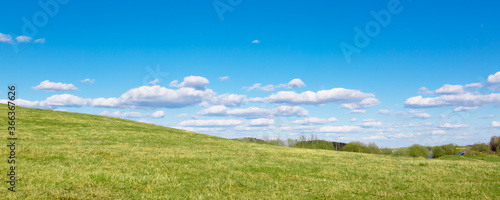 Green field and sun against a blue sky with clouds. The nature of Belarus. A beautiful place to travel and relax with your family. Can be used as a picture for interior decoration.