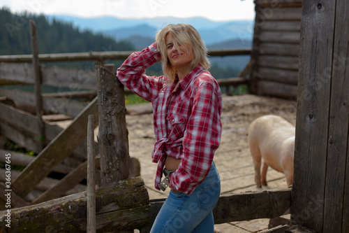 girl in a stylish men's shirt and blue jeans on an old farm