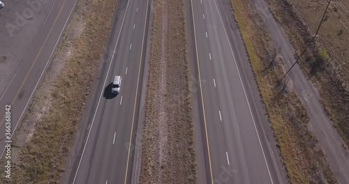 Aerial of Big Straight Highway to Horizon in Dry grass plains showing Trucks and cars going by in United States of America