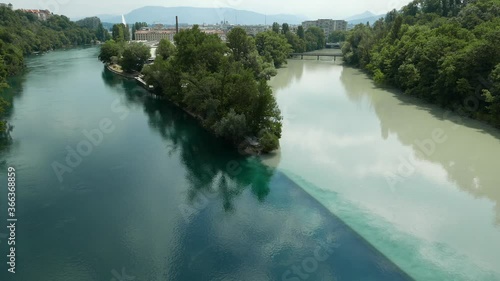 Deep blue-green Rhone and light grey Arve rivers meeting at the Jonction
