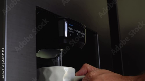 a person draws water from a cooler in the refrigerator.