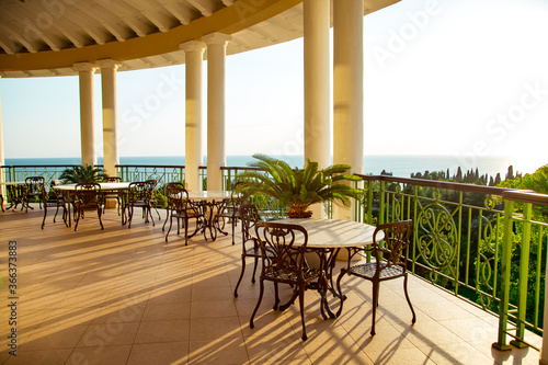 outdoor summer terrace, with cast iron.stylish furniture, in a cafe at sunset