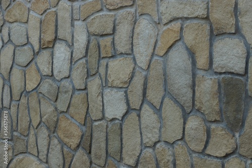 gray brown texture of stones in the wall of the fence on the street