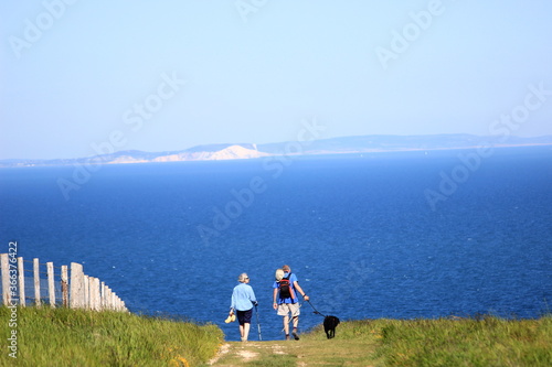 old couple of hikers with a dog walking on the cliffs on the coast of england united kingdom