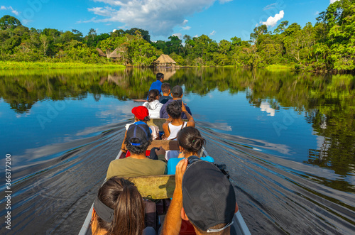 Transport in canoe along the rivers of the Amazon River Basin inside Yasuni National Park with a lodge in traditional architecture style, Ecuador.