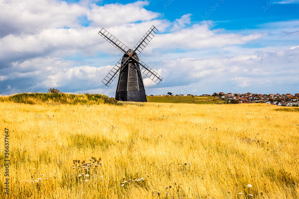 A view across Beacon Hill towards a windmill and the town of Rottingdean, Sussex, UK in summer