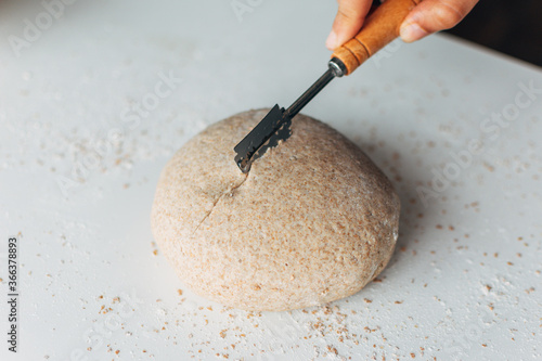 Raw bread dough ball making cross cuts. Scoring bread dough