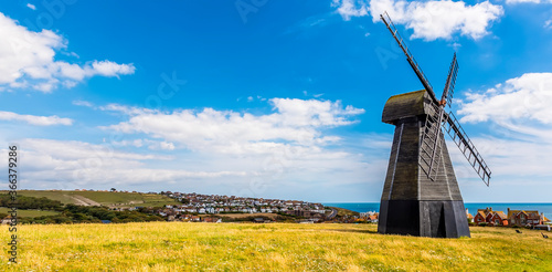 A panorama view across Beacon Hill towards a smock windmill and the town of Rottingdean, Sussex, UK in summer photo