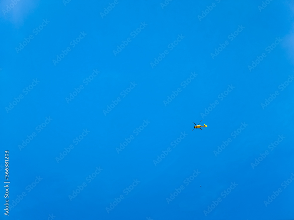 Small yellow helicopter at blue sky