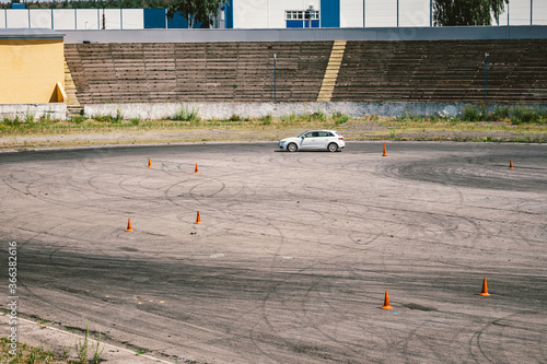 Car and traffic cones, driving school concept. Training car performs exercises on training ground in the driving school. Stadium for safe driving training. Sports complex auto sports. Autodrom photo