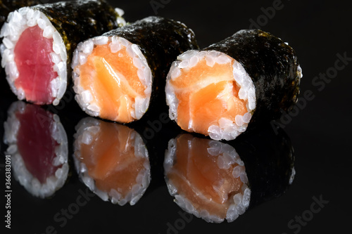 Rolls with salmon, rice, nori, fresh salmon. Several rolls are in one row.