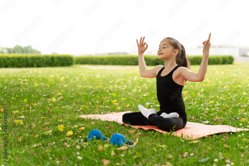 A schoolgirl doing yoga in the grass park. A schoolgirl doing yoga in the grass park.