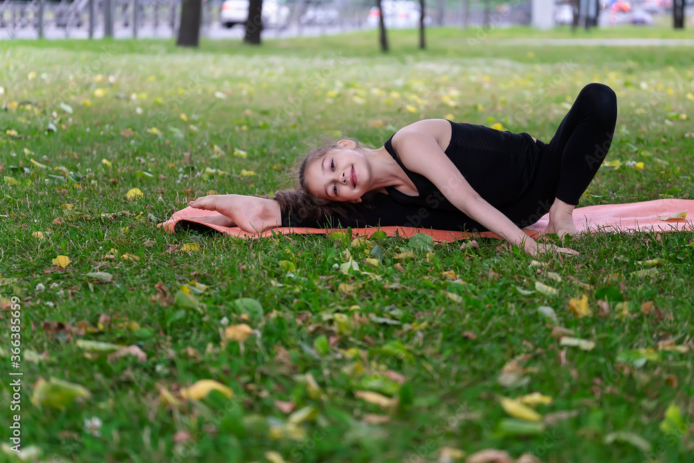 Gymnast schoolgirl warming up in a grass park before performing complex exercises. Gymnast schoolgirl warming up in a grass park before performing complex exercises.