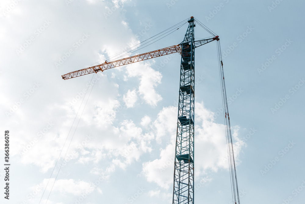 construction crane on the background of a new residential area and cloudy beautiful sky