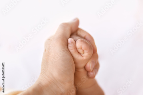 Closeup of newborn baby fist, mother holding infant daughter arm