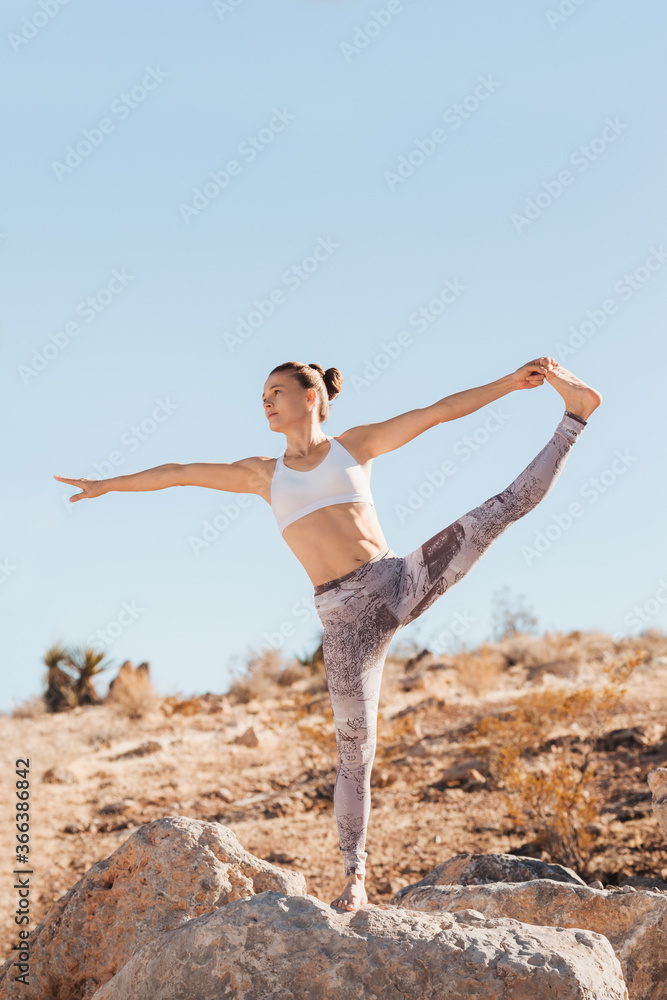 Fit woman in white top practicing yoga in desert on sunny day, health and active life concept Fit woman in white top practicing yoga in desert on sunny day, health and active life concept