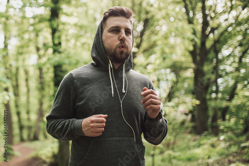 Fototapeta Naklejka Na Ścianę i Meble -  Adult sporty man in forest, park running in the morning