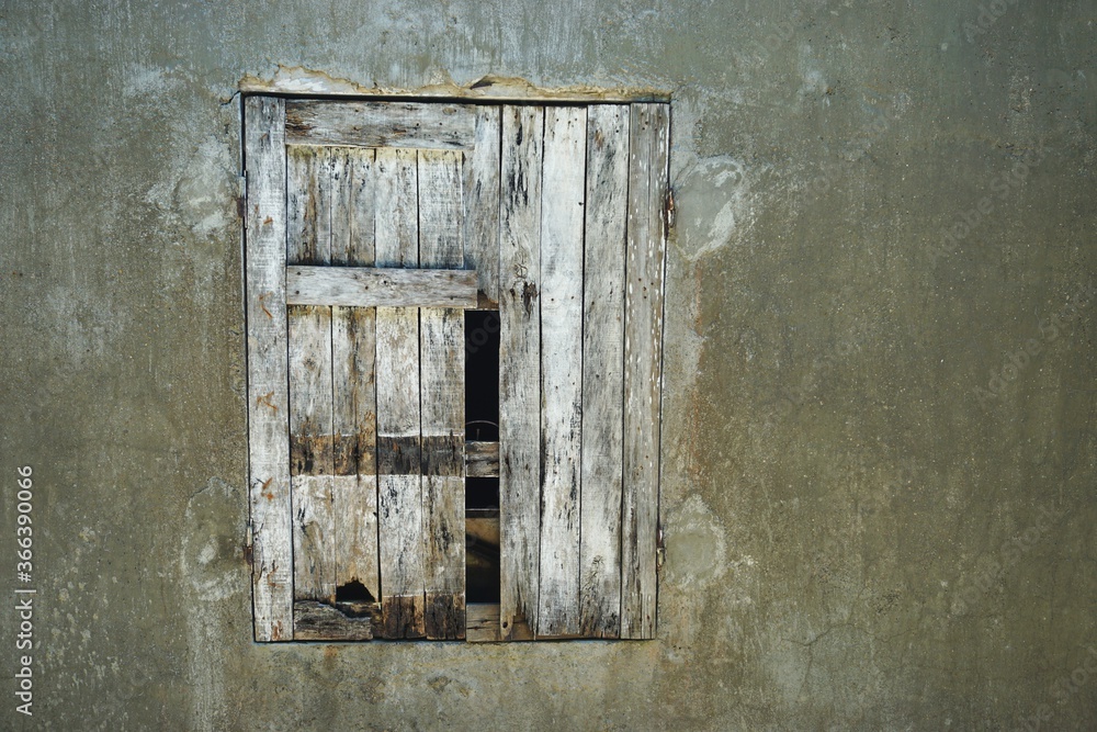 Broken wooden shutter in weathered wall with room for text Broken wooden shutter in weathered wall with room for text