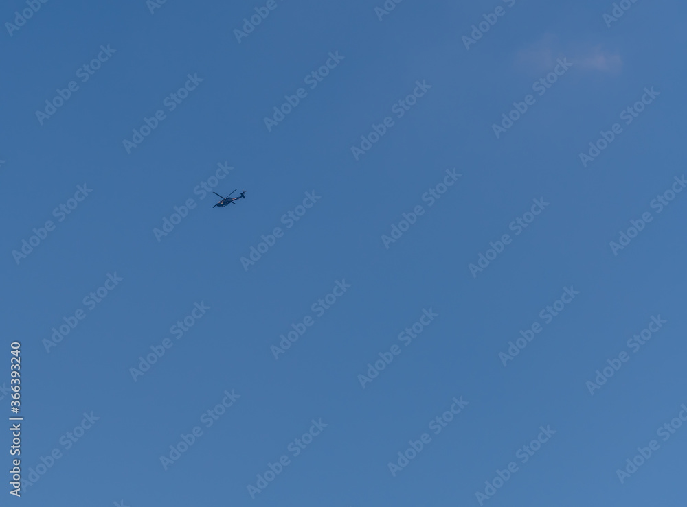 Helicopter flying in clear blue sky.