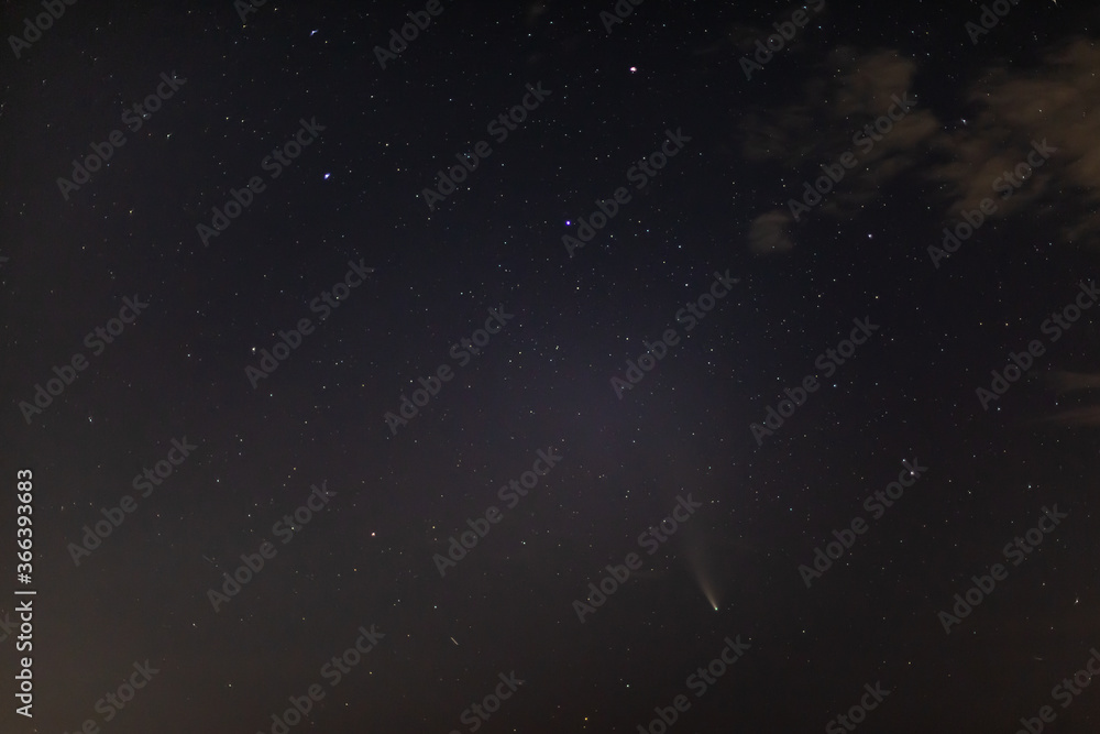 Comet NEOWISE on a dark starry sky with clouds next to the Ursa Major above the horizon at night. Horizontal orientation. Comet NEOWISE on a dark starry sky with clouds next to the Ursa Major above the horizon at night. Horizontal orientation.
