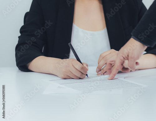 Mano de un hombre de negocios señalando dónde firmar el documento. Colegas firmando documentos en la oficina.
