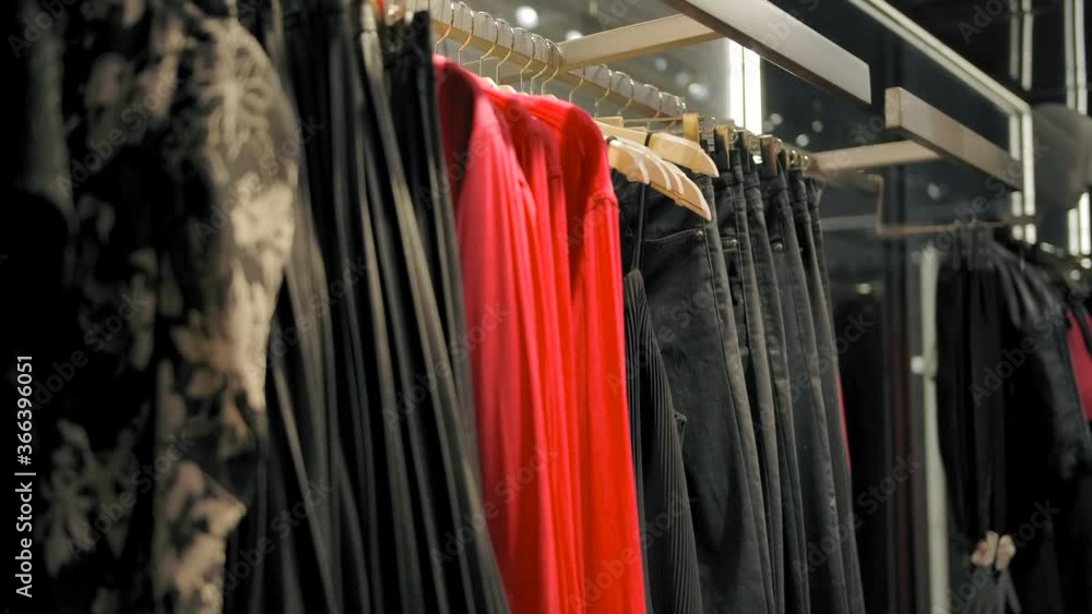 Hangers with dresses, pants and shirts in the clothing store. Slow motion handheld shot. Hangers with dresses, pants and shirts in the clothing store. Slow motion handheld shot.