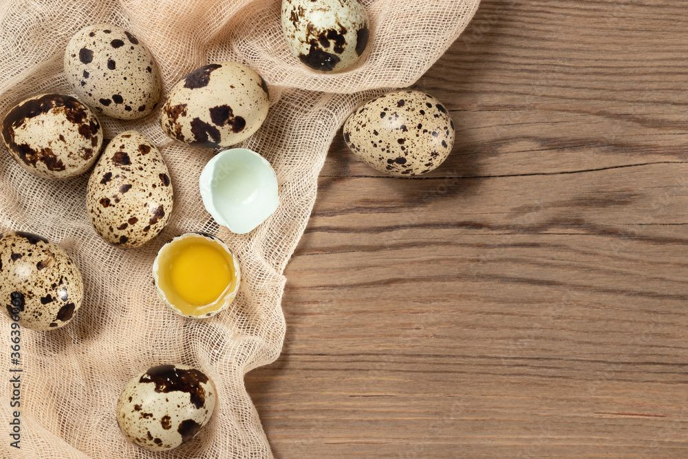 Composition of several quail eggs on decorative fabric on a wooden table, copy space, flatlay Composition of several quail eggs on decorative fabric on a wooden table, copy space, flatlay