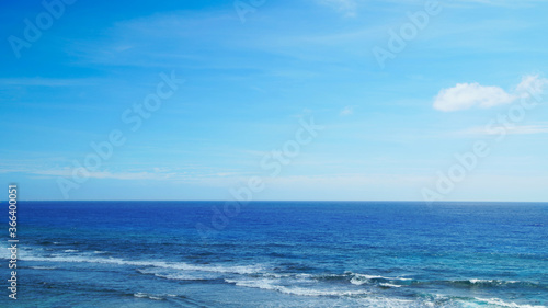 Horizon seascape with blue sky, waves on the water of a sandy beach