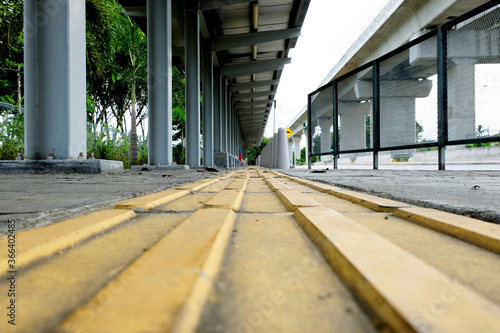 Yellow tactile paving guide path leading to a bus stand, installed to assist the visually impaired passengers and pedestrians. photo