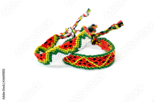 Selective focus of tied woven friendship bracelets with watermelon pattern handmade of thread isolated on white background