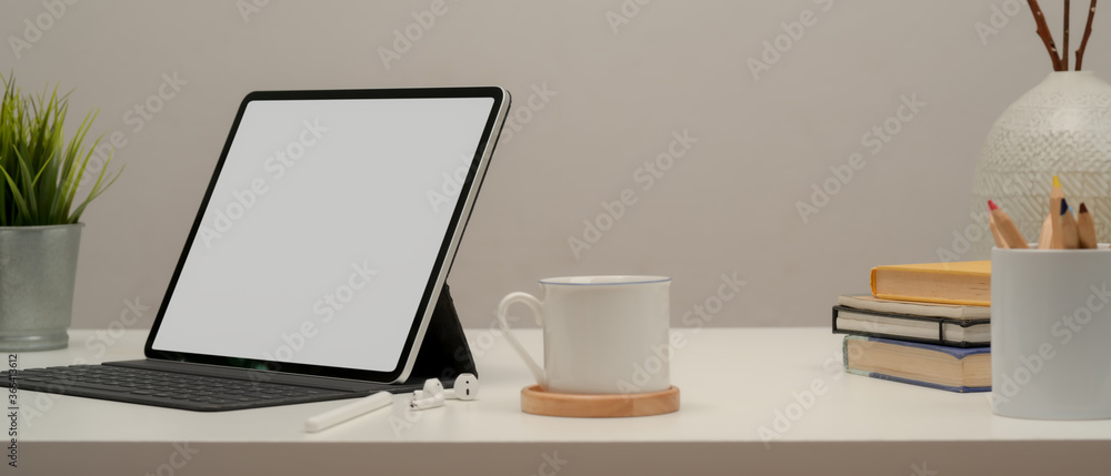 Blank screen tablet on white table with coffee cup, stationery and decorations Blank screen tablet on white table with coffee cup, stationery and decorations