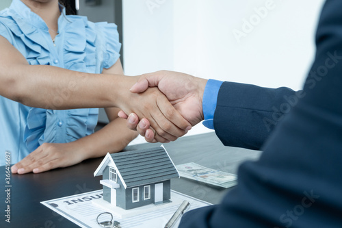 A real estate agent and clients shake hands after completing the home insurance contract negotiation and signing a formal contract. Rental and home insurance concepts