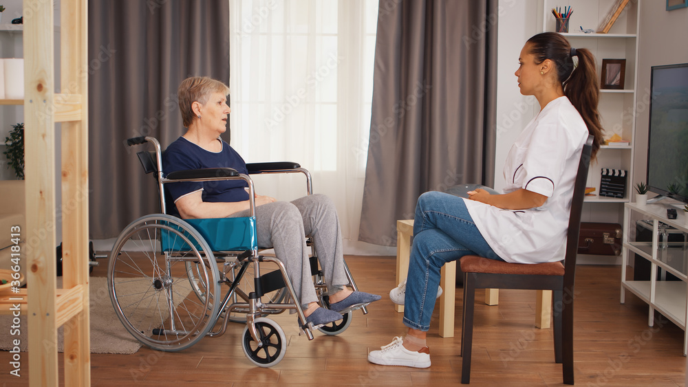 Disabled senior woman in wheelchair talking with doctor. Old person retirement home, healthcare nursing, health support, social assistance, doctor and home service
